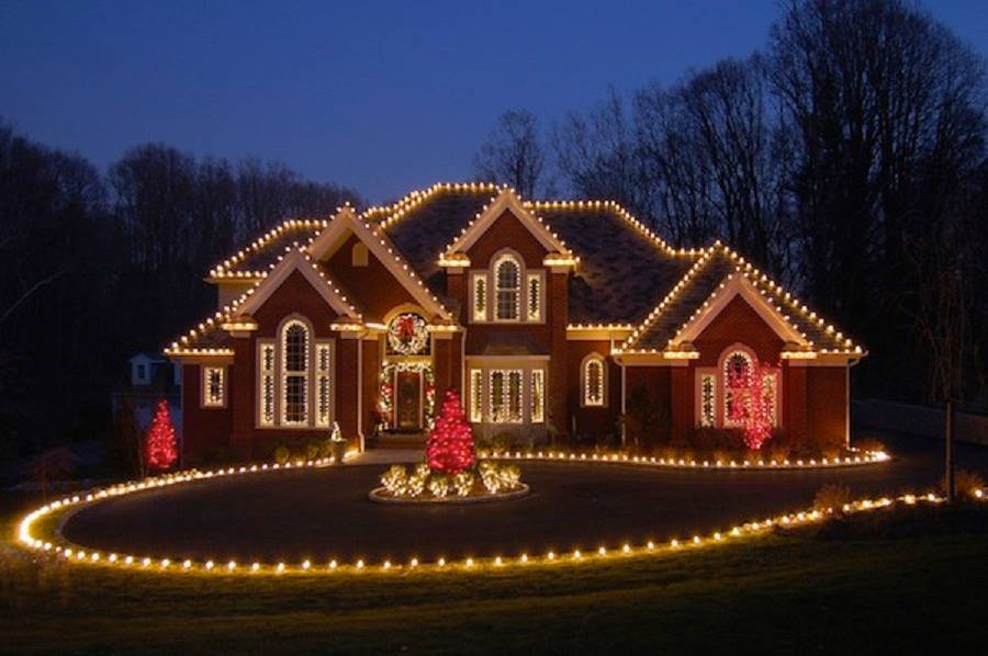 Home at night with warm-white C9 roofline Christmas lights, lit wreath and entry garland